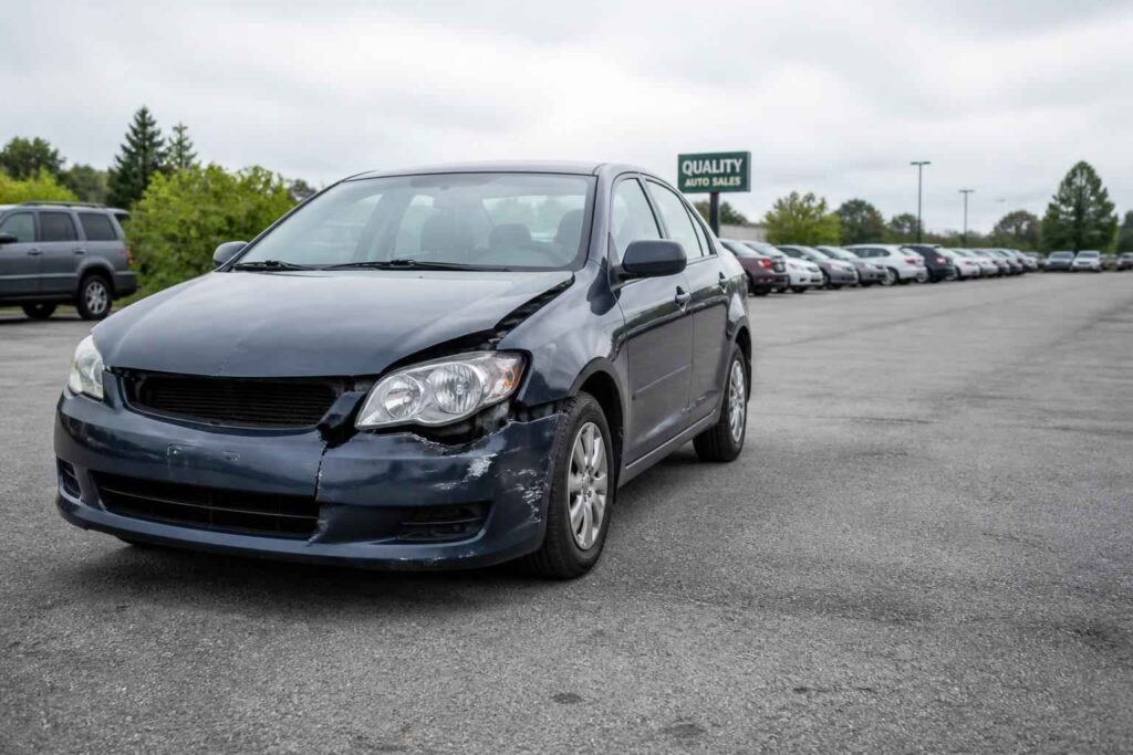 Ciemny sedan przed salonem samochodowym Ciemny sedan zaparkowany na placu sprzedaży samochodów pod pochmurnym niebem