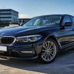 Granatowe BMW Serii 5 zaparkowane na dachu parkingu w słoneczny dzień