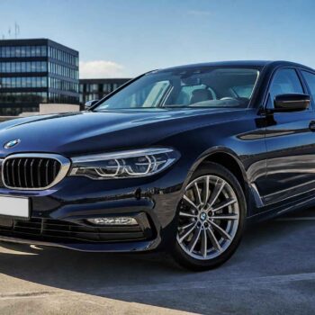 Granatowe BMW Serii 5 zaparkowane na dachu parkingu w słoneczny dzień